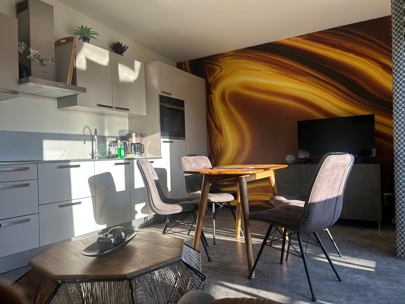 Küche mit Essbereich und Wandbild. Tisch mit Stühlen und TV.