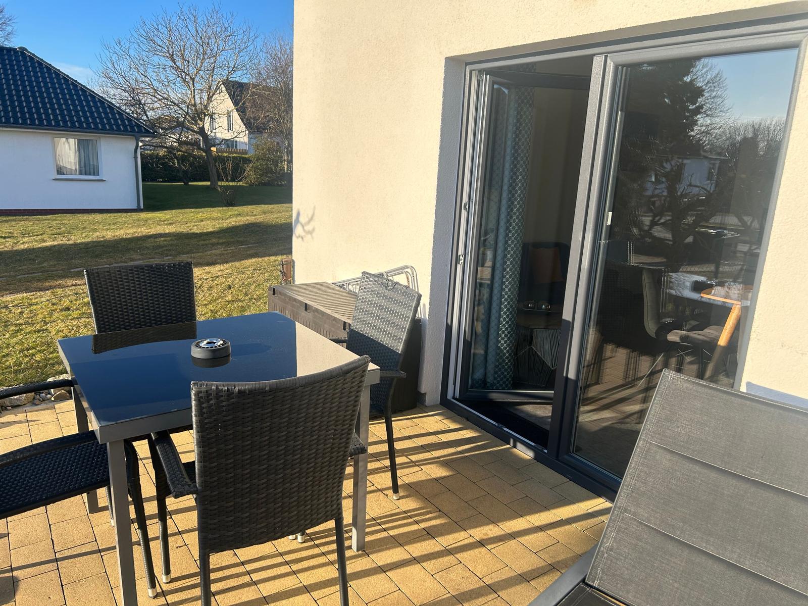 Terrasse mit Tisch, Stühlen und Schiebetür zum Innenraum.