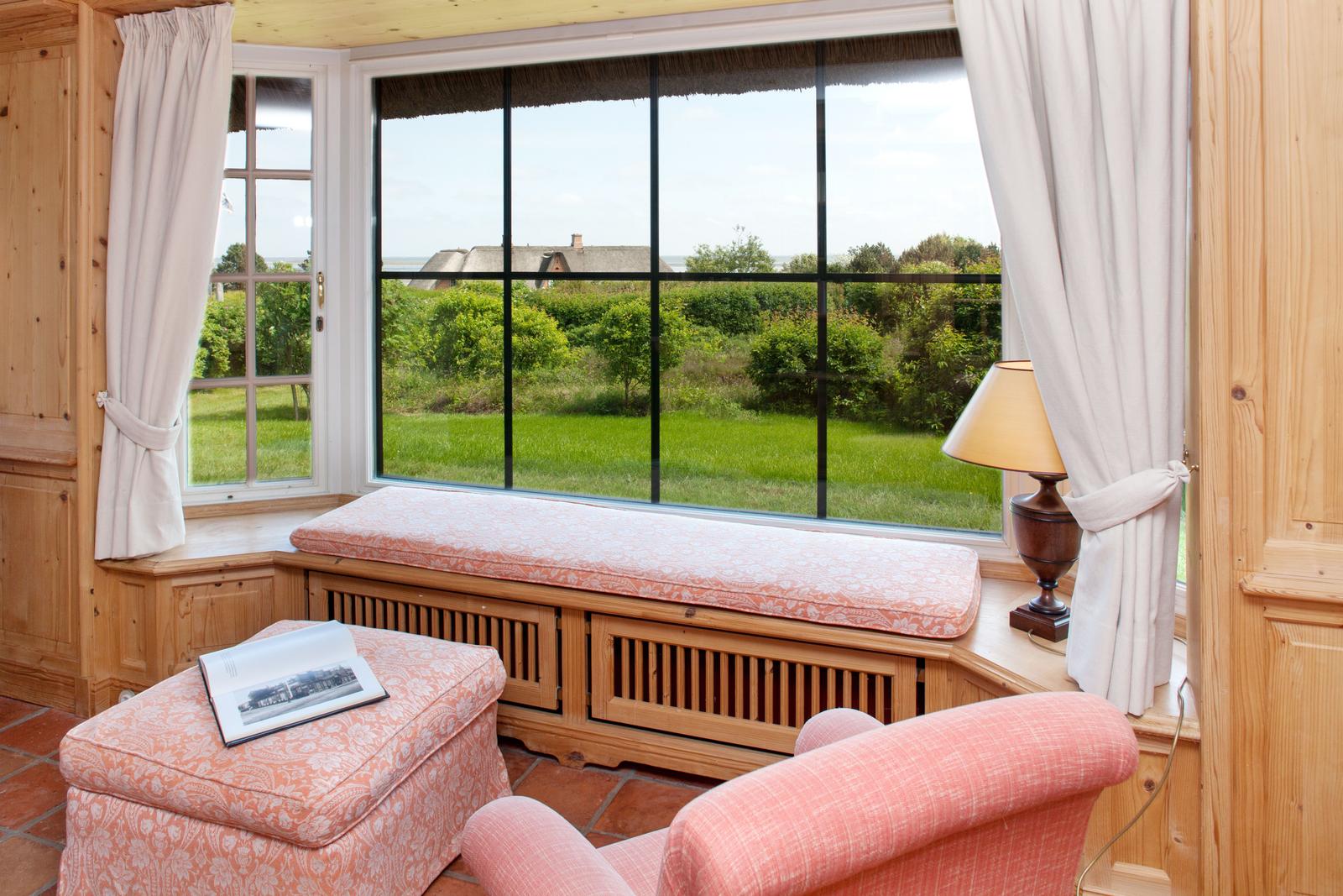 Sitzgelegenheit mit Blick auf grüne Landschaft durch großes Fenster.