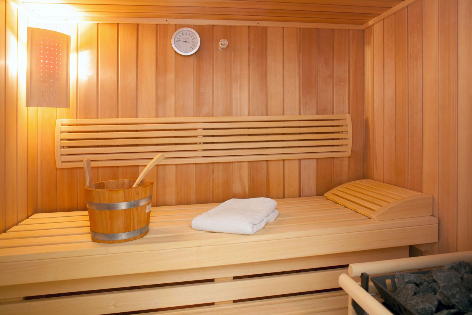 Sauna mit Holzbank, Eimer und Handtuch.