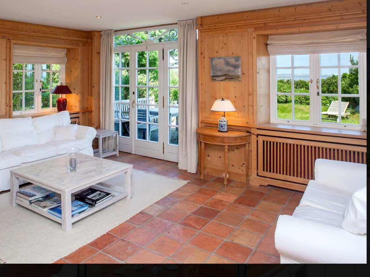 Wohnzimmer mit Holzwand, Terrasse und Meerblick durch Fenster.