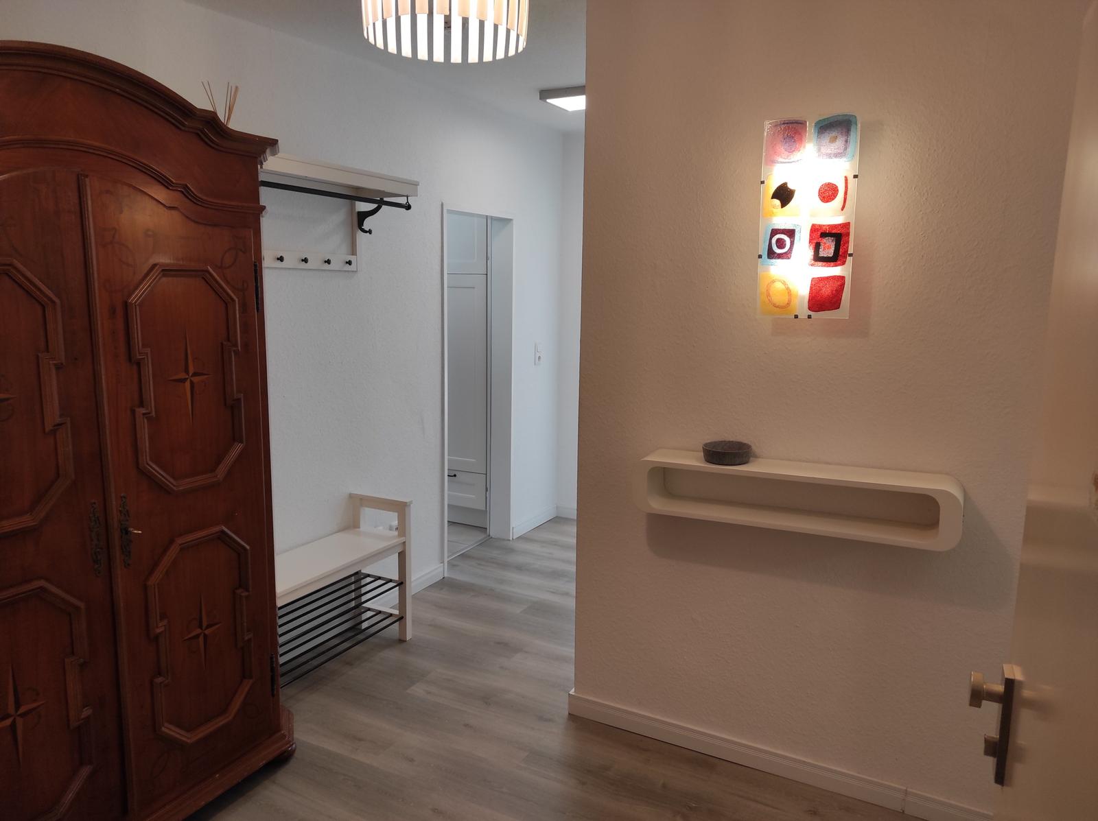 Eingangsbereich mit Holzschrank, Wandlampe und Kleiderständer
