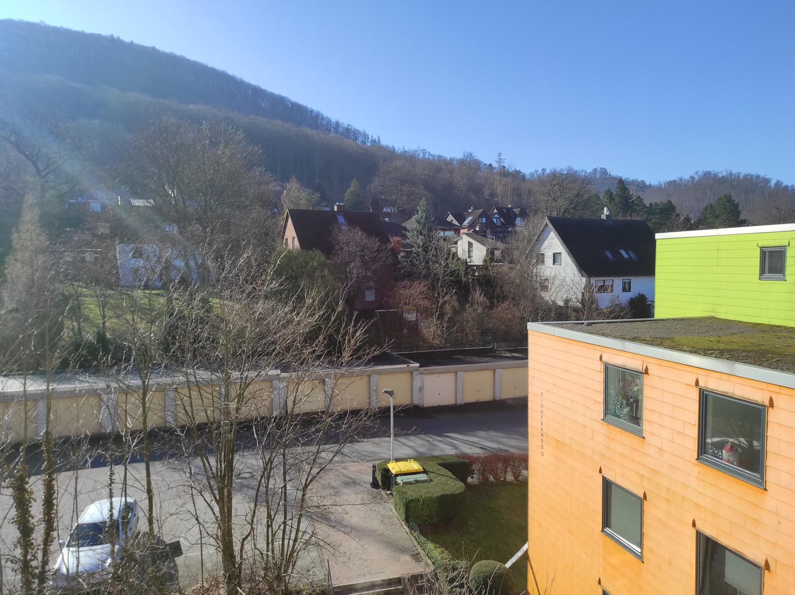Blick auf Wohngebiet mit grüner Fassade und Berg im Hintergrund.