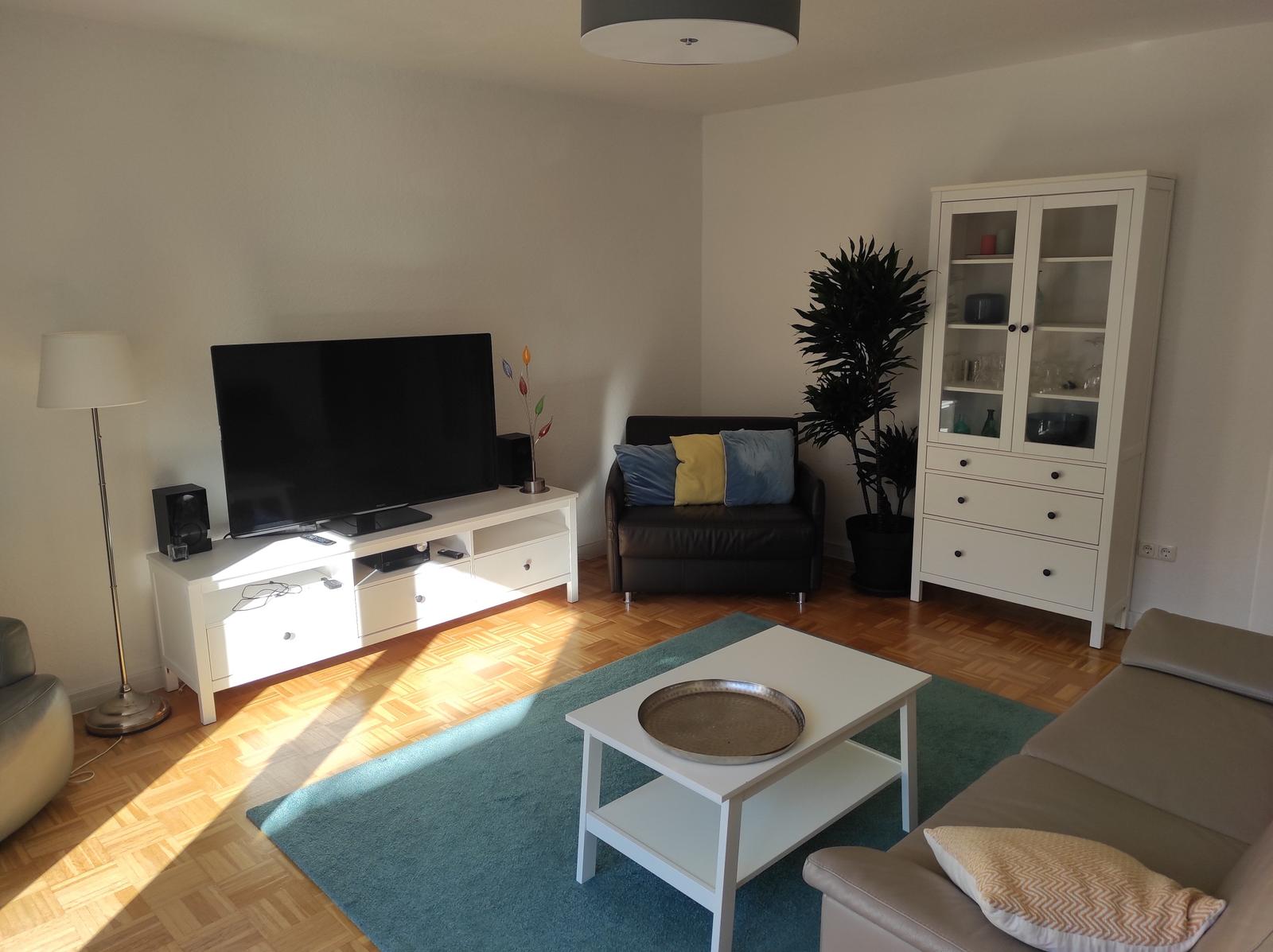 Wohnzimmer mit Sofa, Fernseher und Schrank.