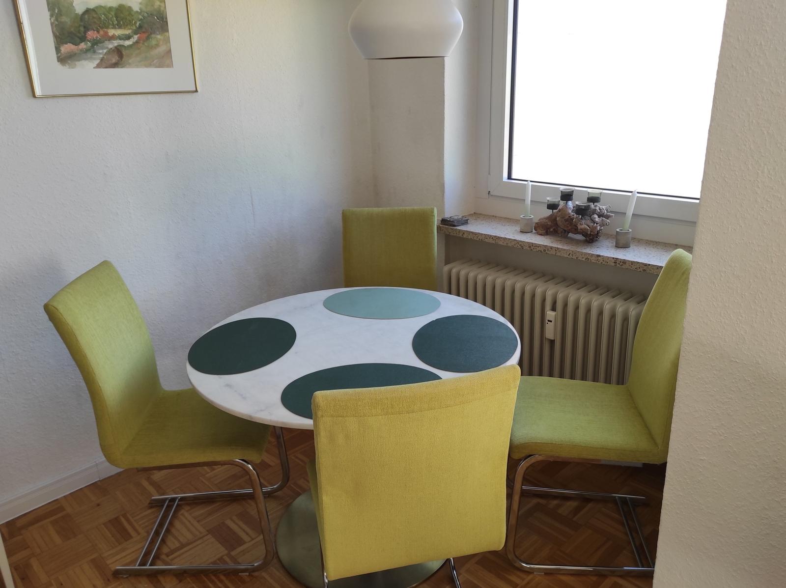 Rundtisch mit vier grünen Stühlen und Fenster