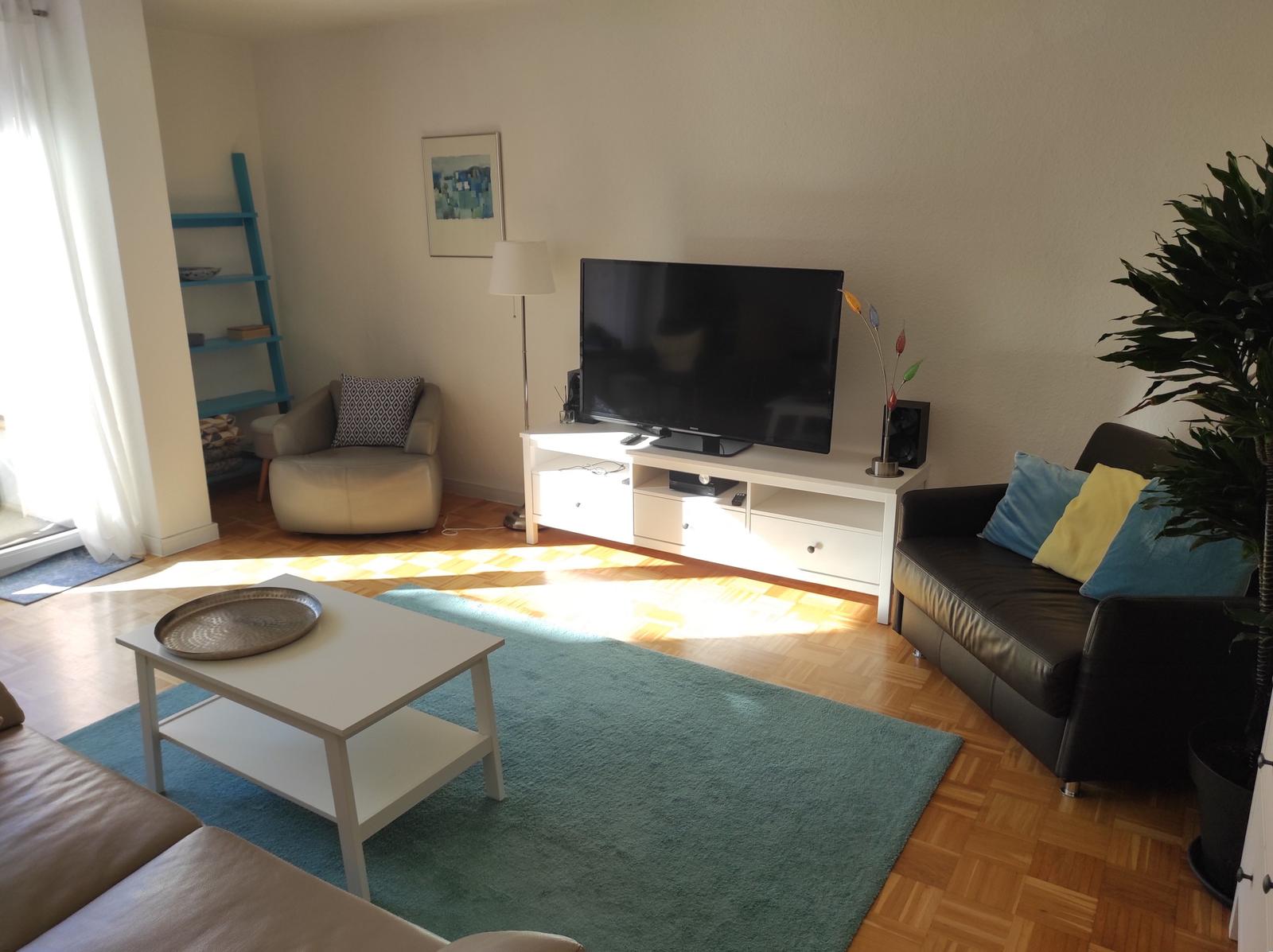 Wohnzimmer mit Sofa, Fernseher und Holzboden.