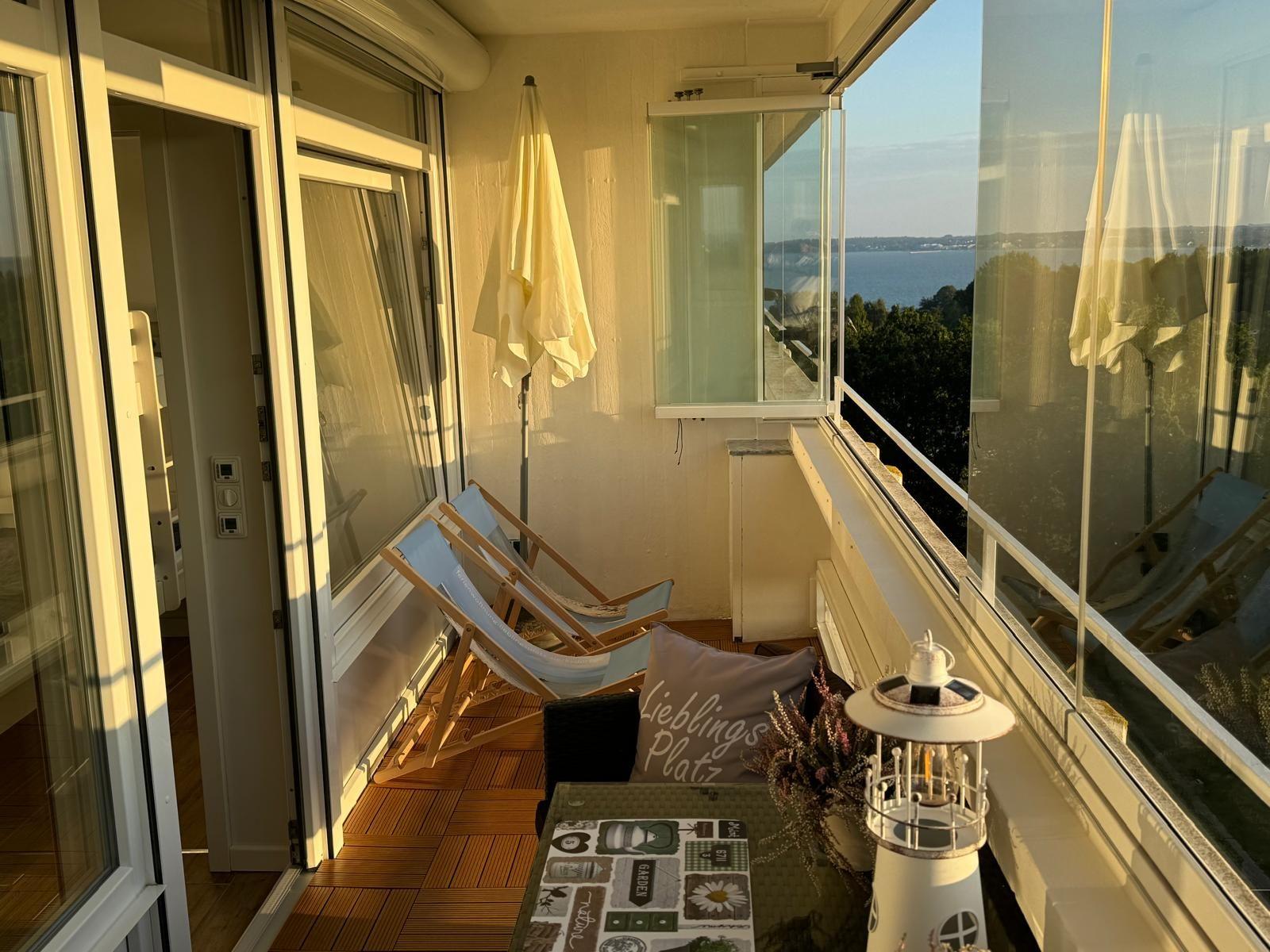 Terrasse mit Liegestühlen und Meerblick. Gelber Sonnenschirm und Tisch mit Dekoration.