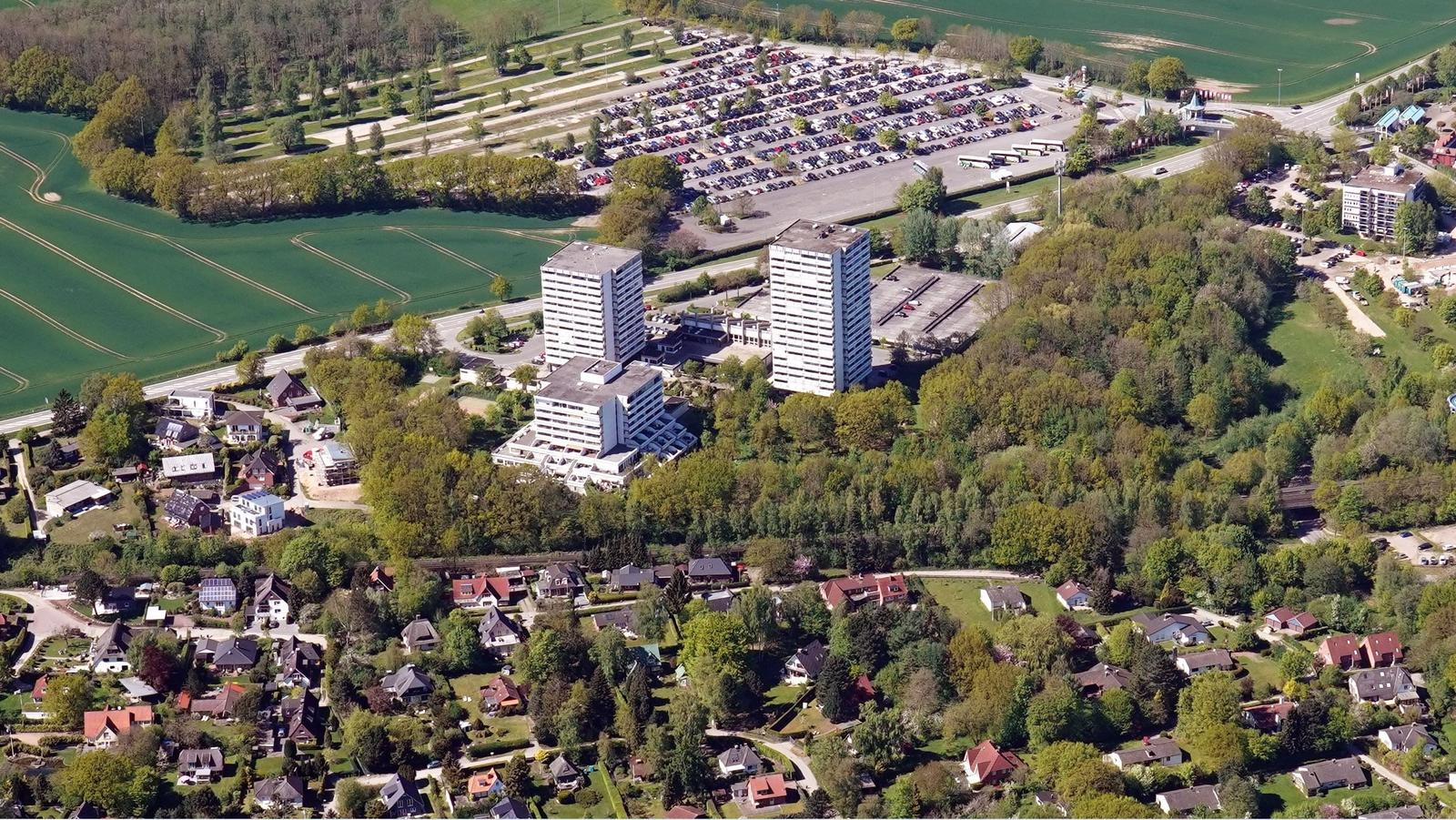 Luftbild von Wohngebieten, Hochhäusern und grünen Flächen mit Parkplatz.