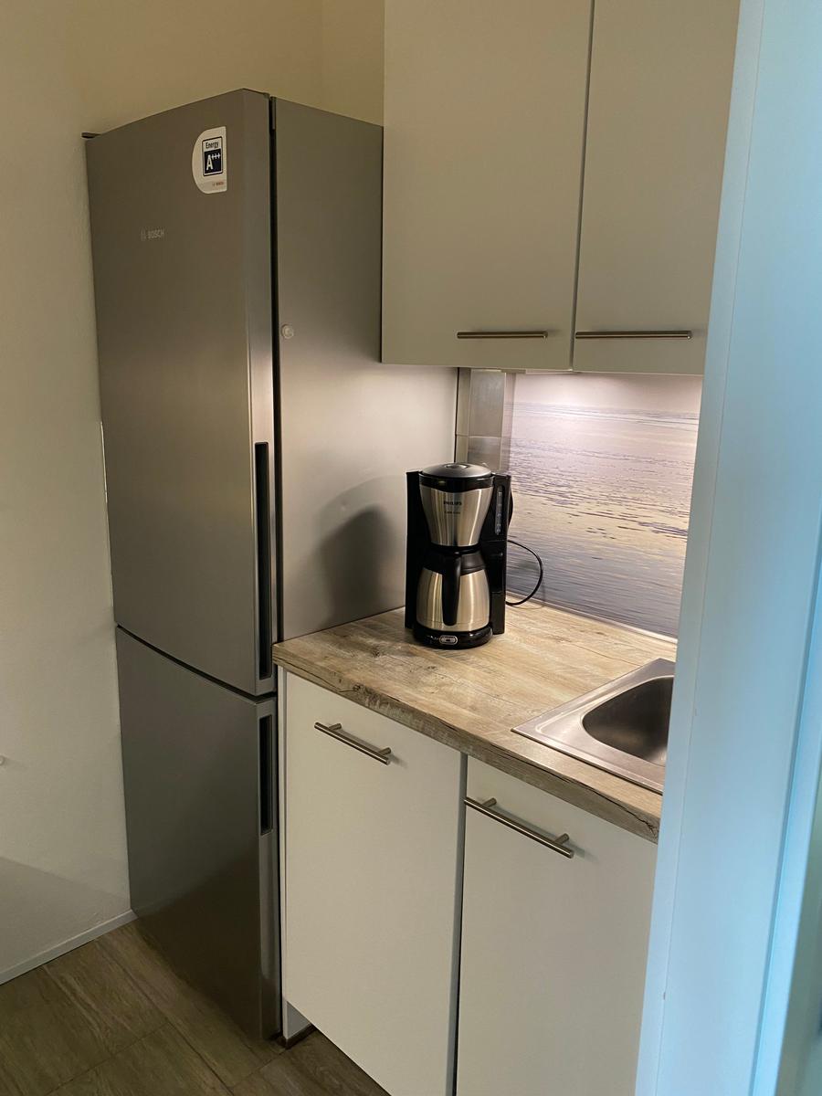 Küche mit Kühlschrank, Arbeitsplatte und Spüle.