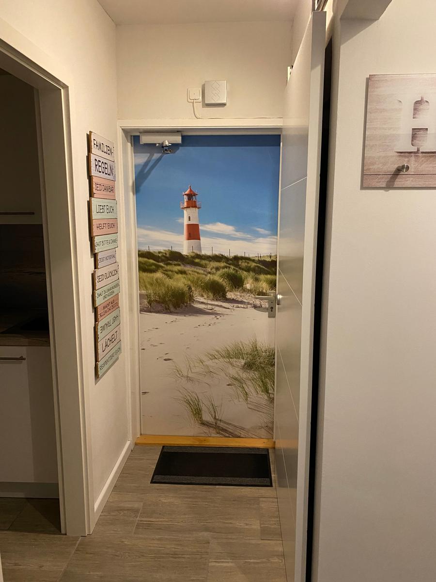 Eingangsbereich mit Leuchtturm-Bild an Tür und Wandtafel mit Regeln.