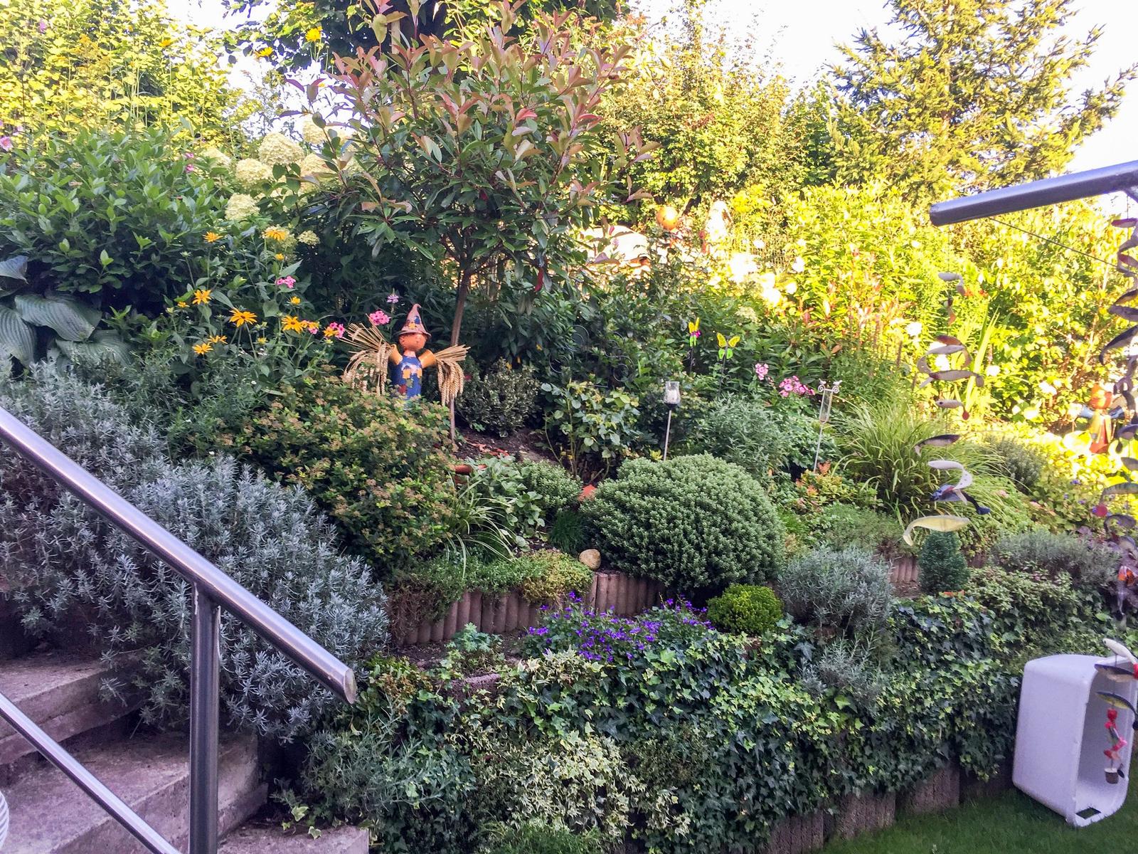 Garten mit Stufen, Pflanzen und dekorativen Figuren