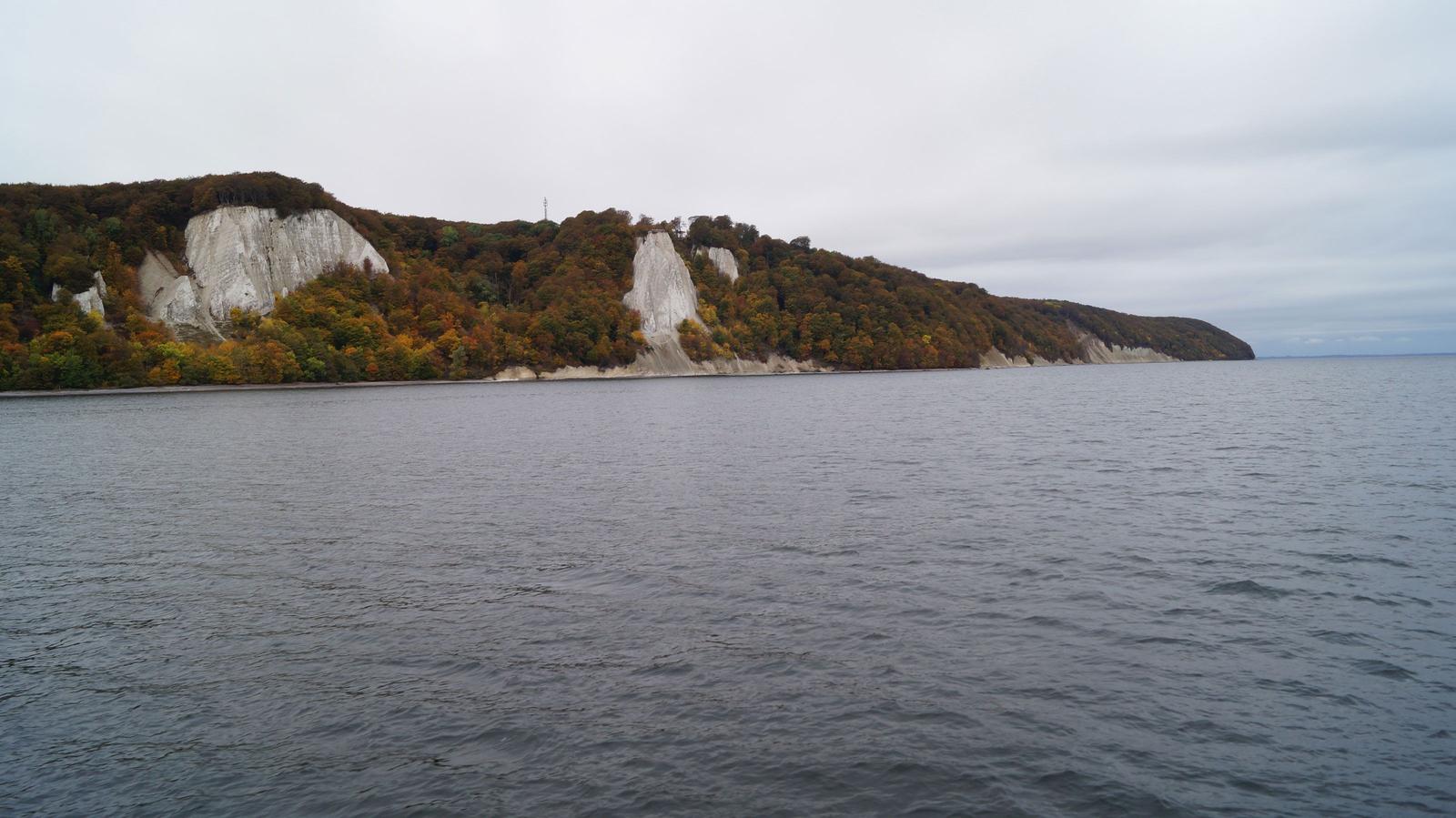Weitläufiger Blick auf Küstenlandschaft mit weißen Felsen und farbenfrohem Herbstwald.
