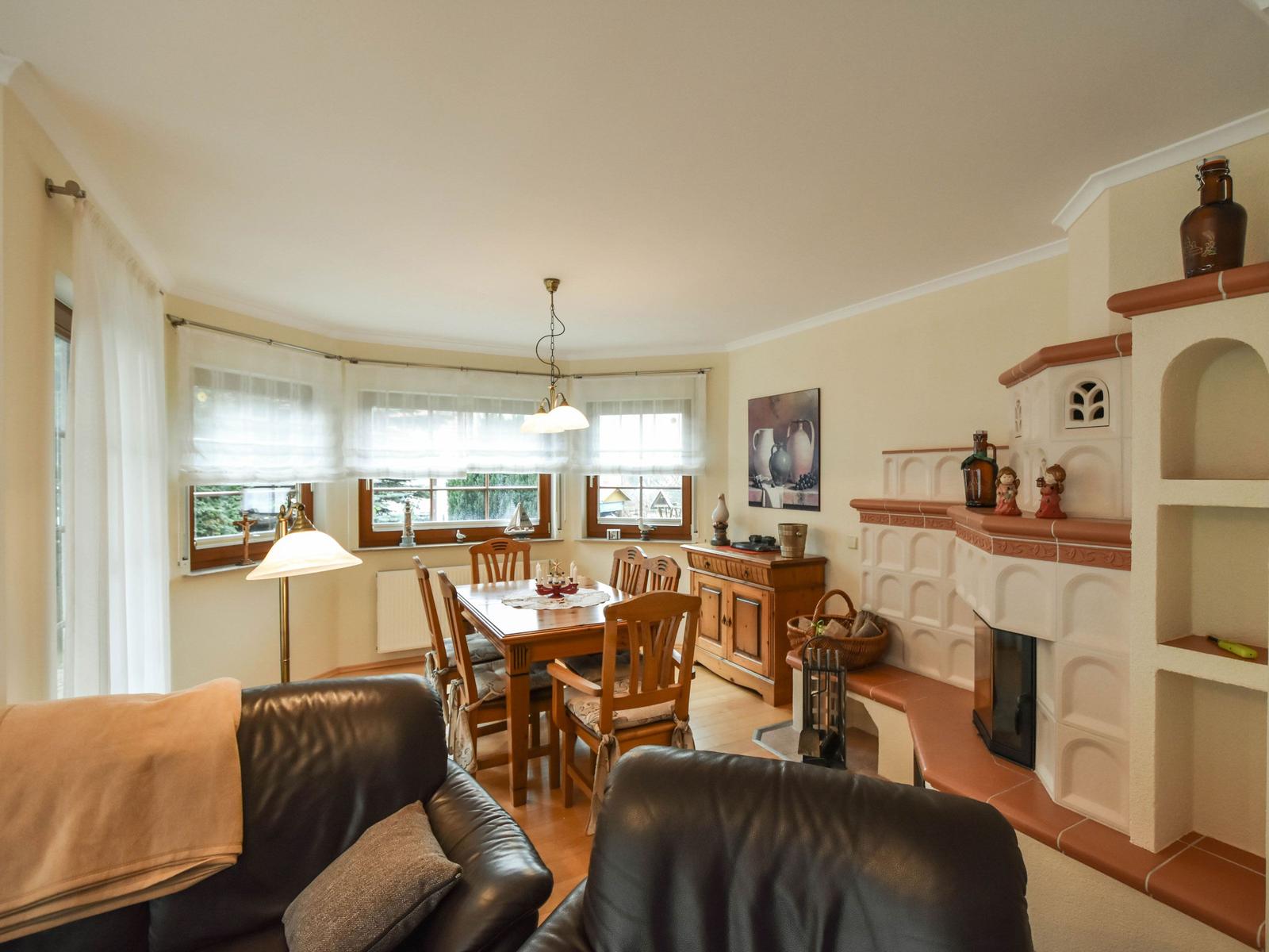 Wohn- und Essbereich mit Holztisch, Ledersofa und Kamin.