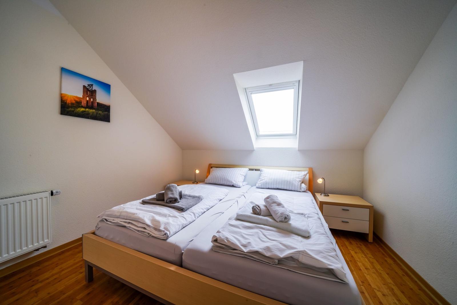 Doppelbett mit Fenster, Nachttische und Wandbild.