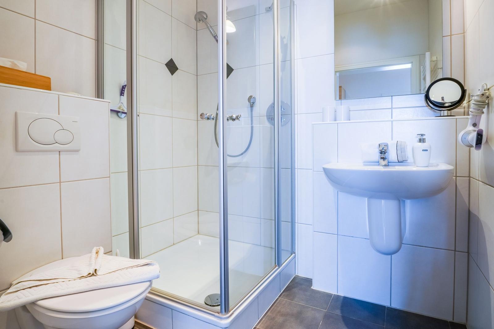 Badezimmer mit Dusche, Waschbecken und Toilette.