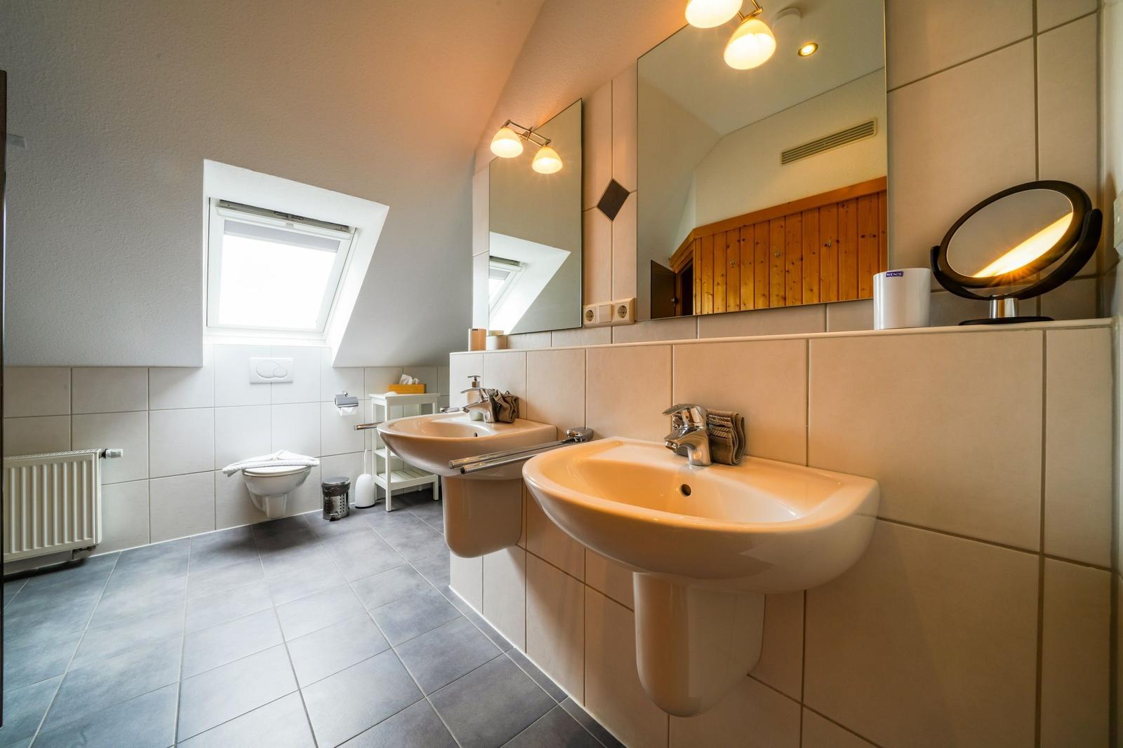 Badezimmer mit zwei Waschbecken, Spiegel und Dachfenster.