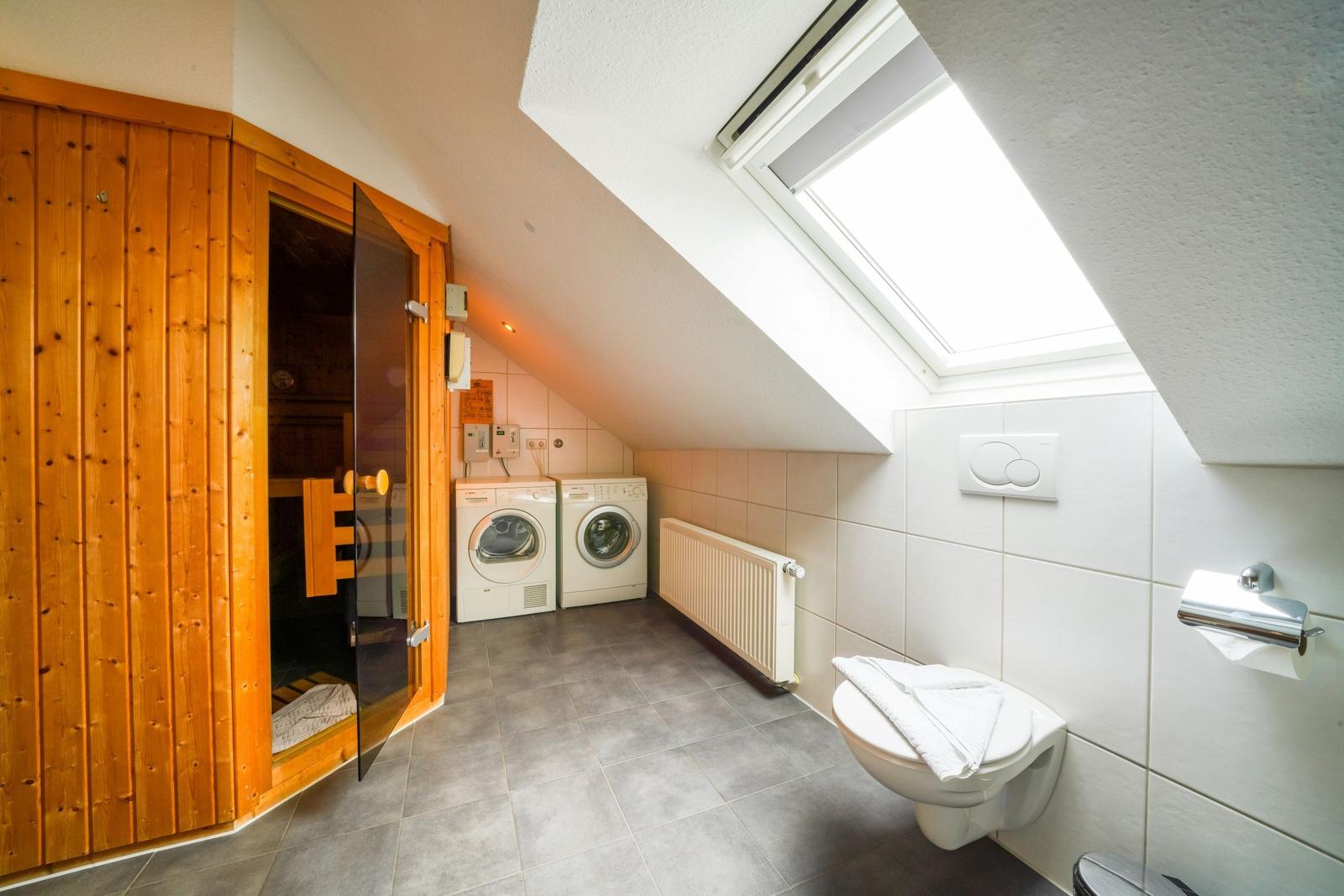 Dachbodenbereich mit Sauna, Waschmaschine und Toilette unter Dachschräge mit Dachfenster.