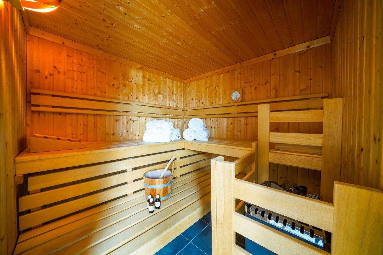 Sauna mit Holzbänken, Handtuchstapel und Holzschale.
