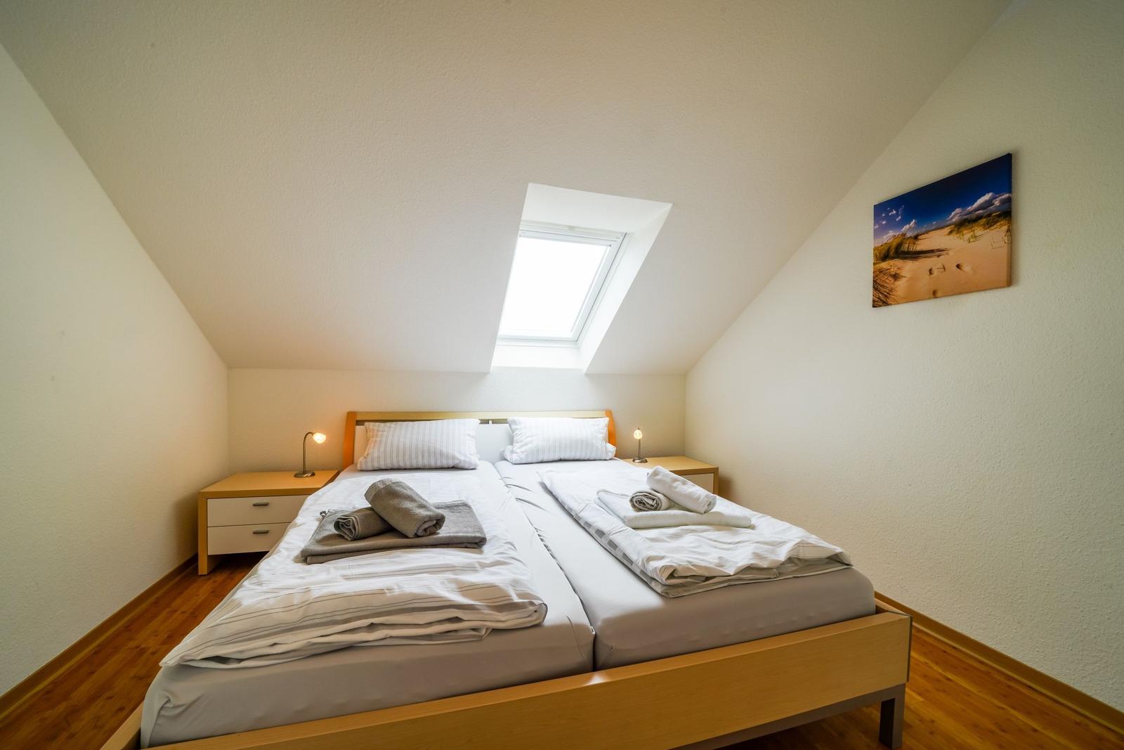 Schlafzimmer mit Doppelbett, Dachfenster und Wandbild