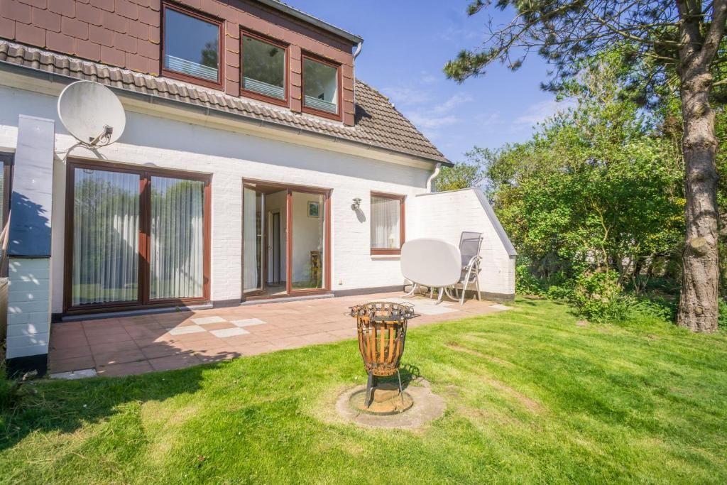 Wohnhaus mit Terrasse, Grill und Garten. Satellitenschüssel und Bäume sichtbar.