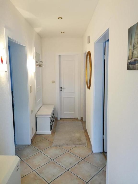 Flur mit weißen Wänden, gefliestem Boden und Tür zu einem Raum