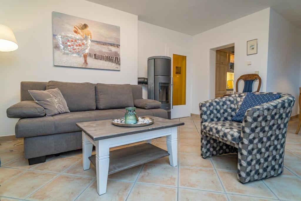 Wohnzimmer mit Sofa, Sessel und Kaminofen. Wandbild und Holztisch.