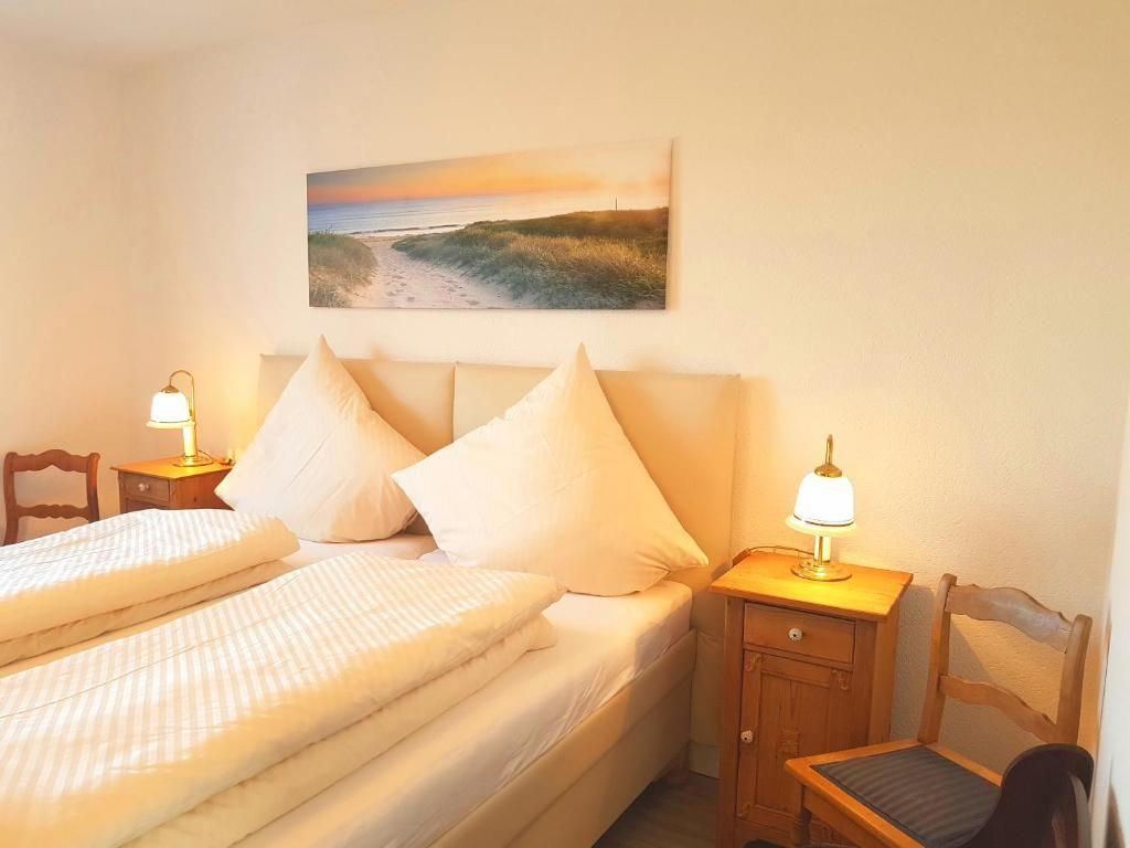 Schlafzimmer mit Bett, zwei Nachttischen und Stühlen. Wandbild zeigt Strand.