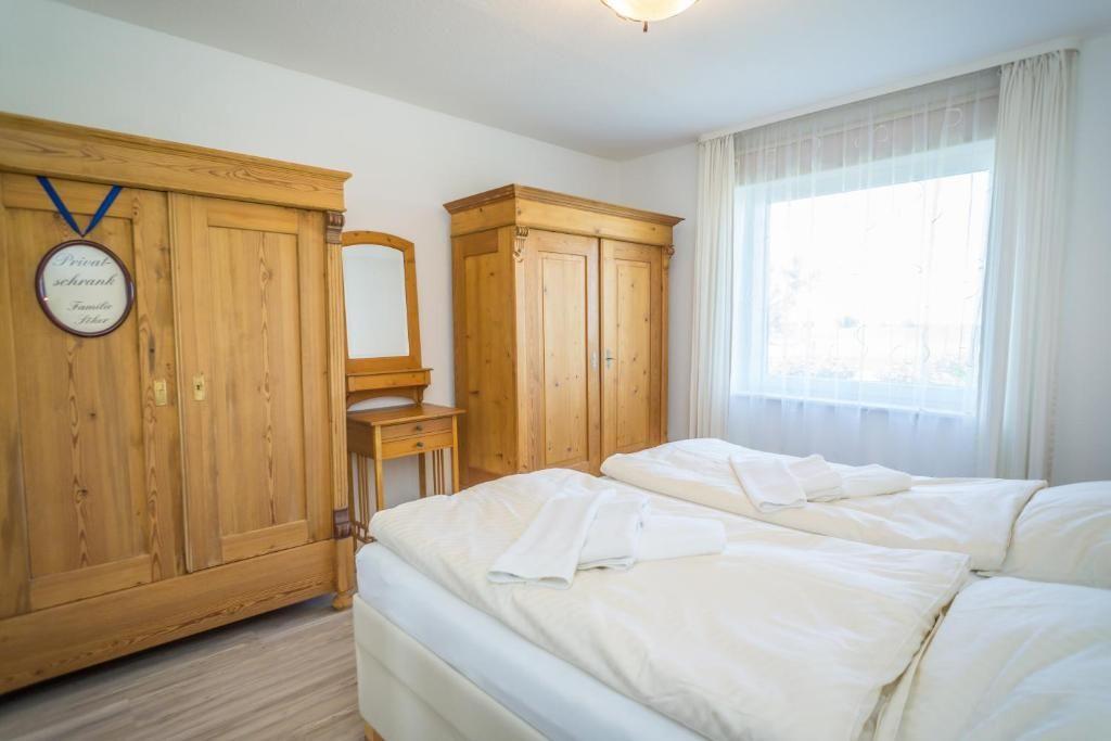 Schlafzimmer mit Holzschrank, Spiegel und Fenster mit Vorhängen.