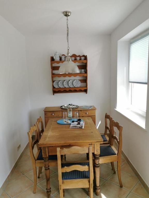 Esszimmer mit Holztisch, Stühlen und Wandregal mit Geschirr.