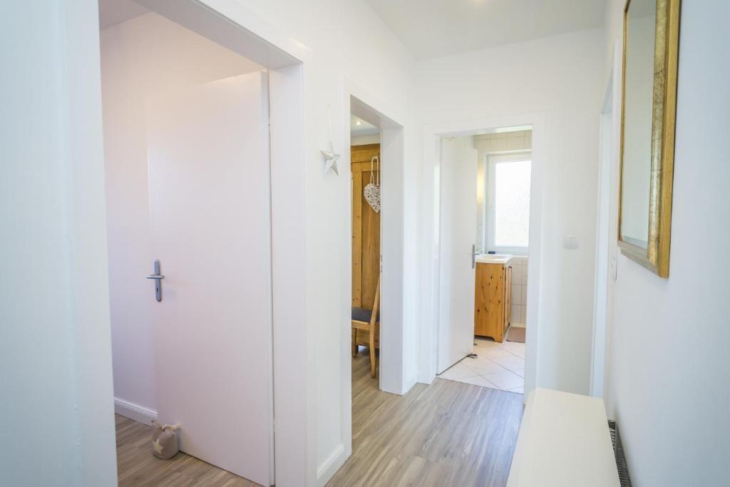 Flur mit Türen zu Schlafzimmer und Bad, Holzboden und Spiegel an der Wand.