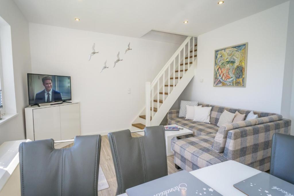 Wohn- und Essbereich mit Sofa, TV und Treppe.