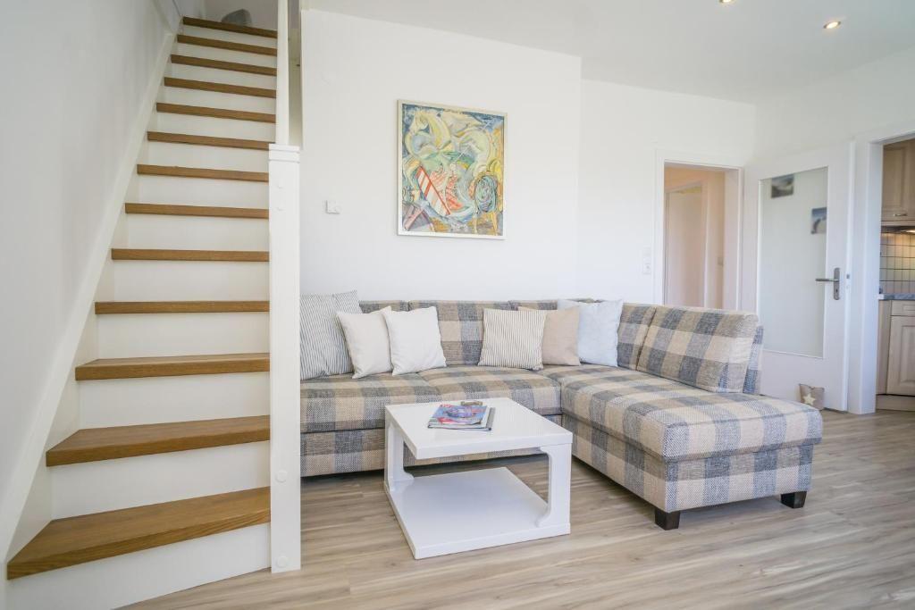 Wohnzimmer mit Ecksofa, Treppe und Wandbild.