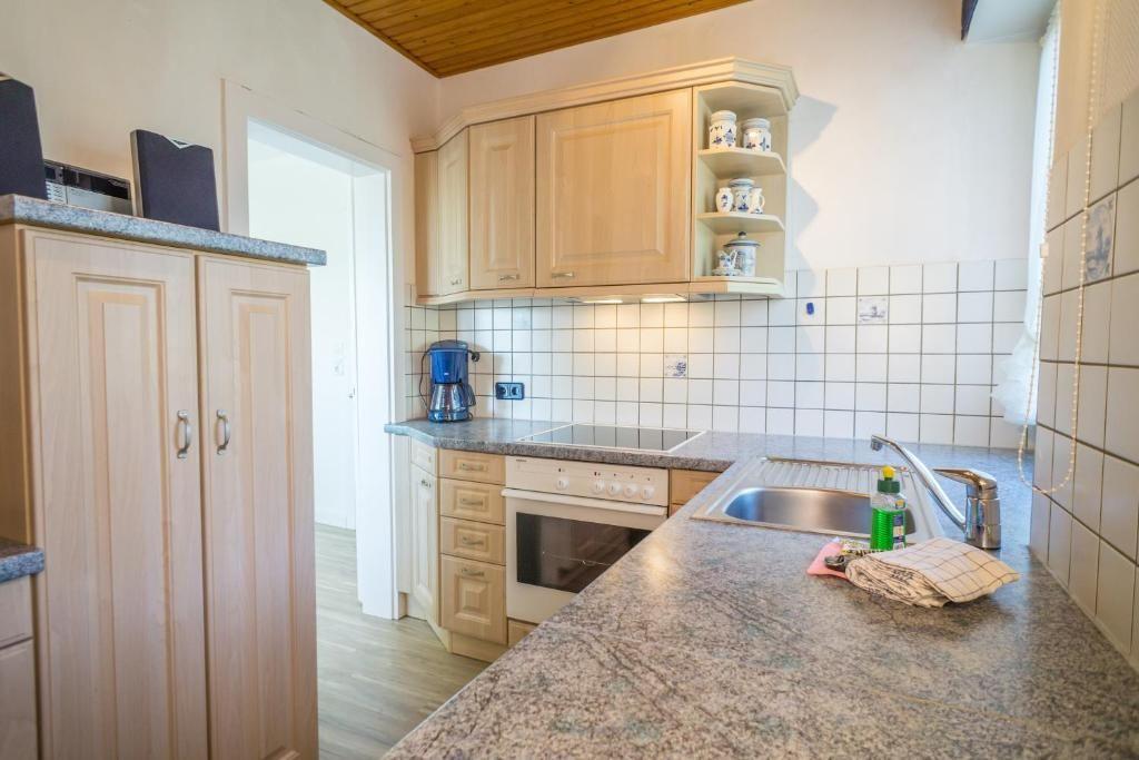 Küche mit Holzschränken, Granitplatte und Edelstahlspüle.