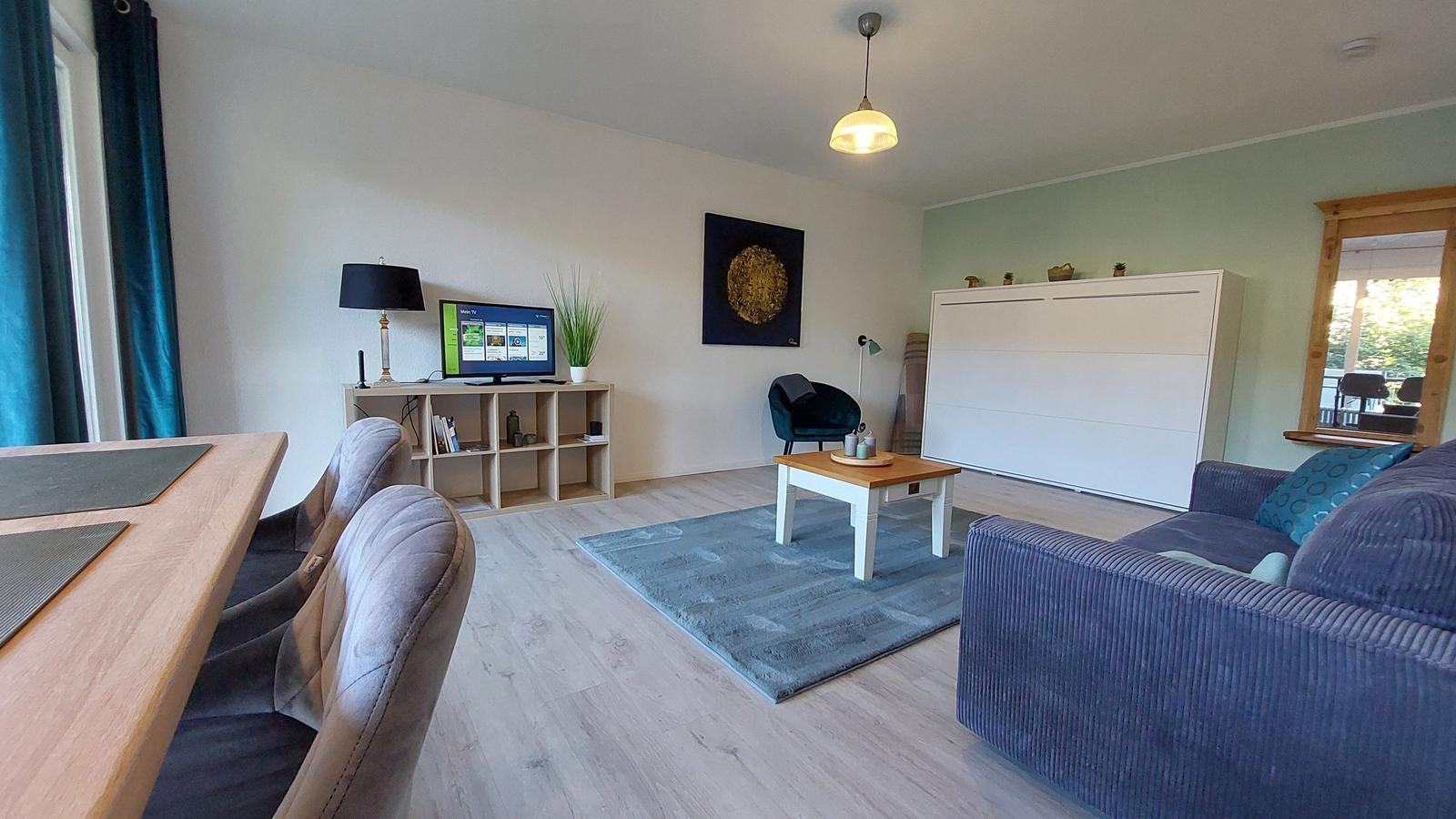 Wohnzimmer mit Sofa, Couchtisch und Fernseher an der Wand.