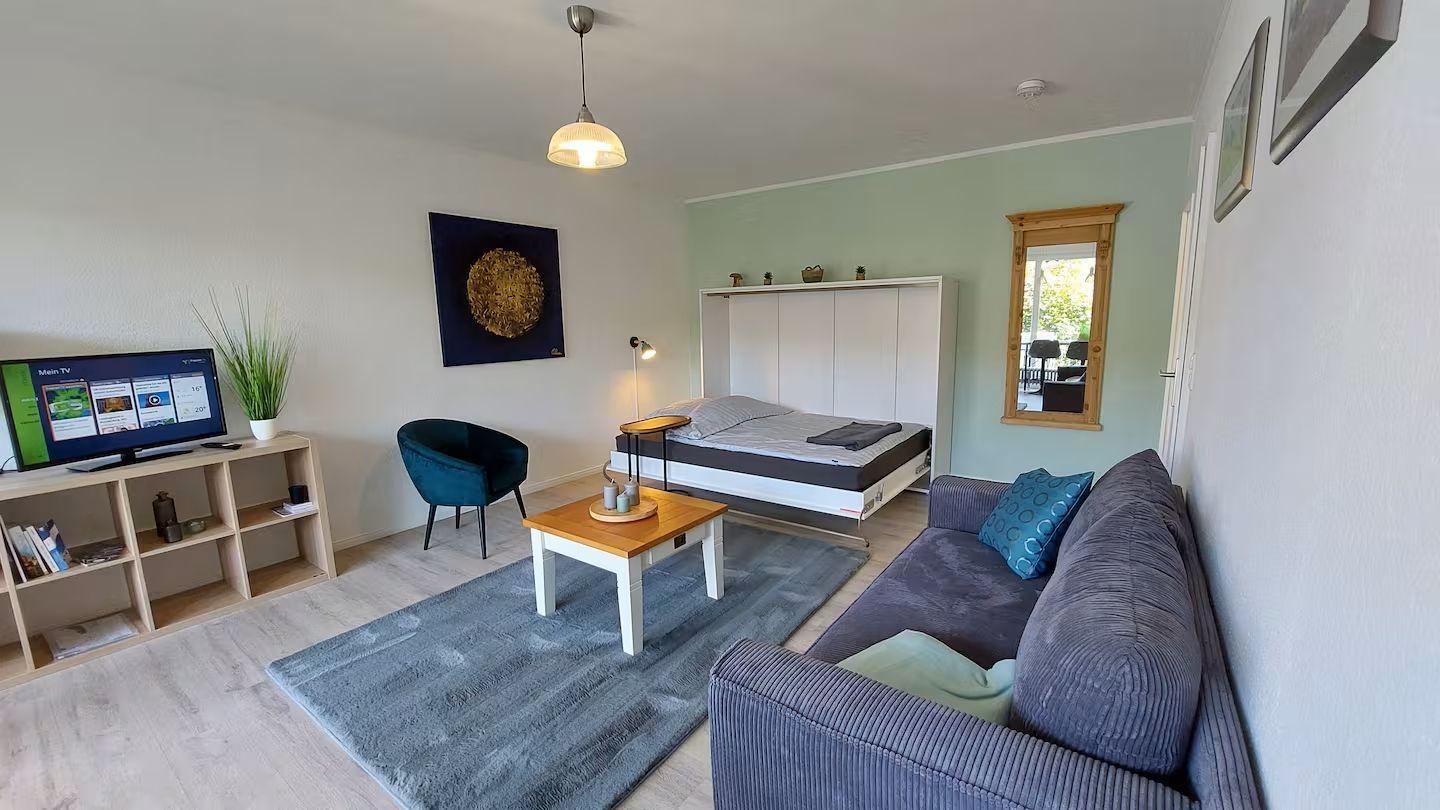 Wohnzimmer mit Sofa, Bett und Fernseher.