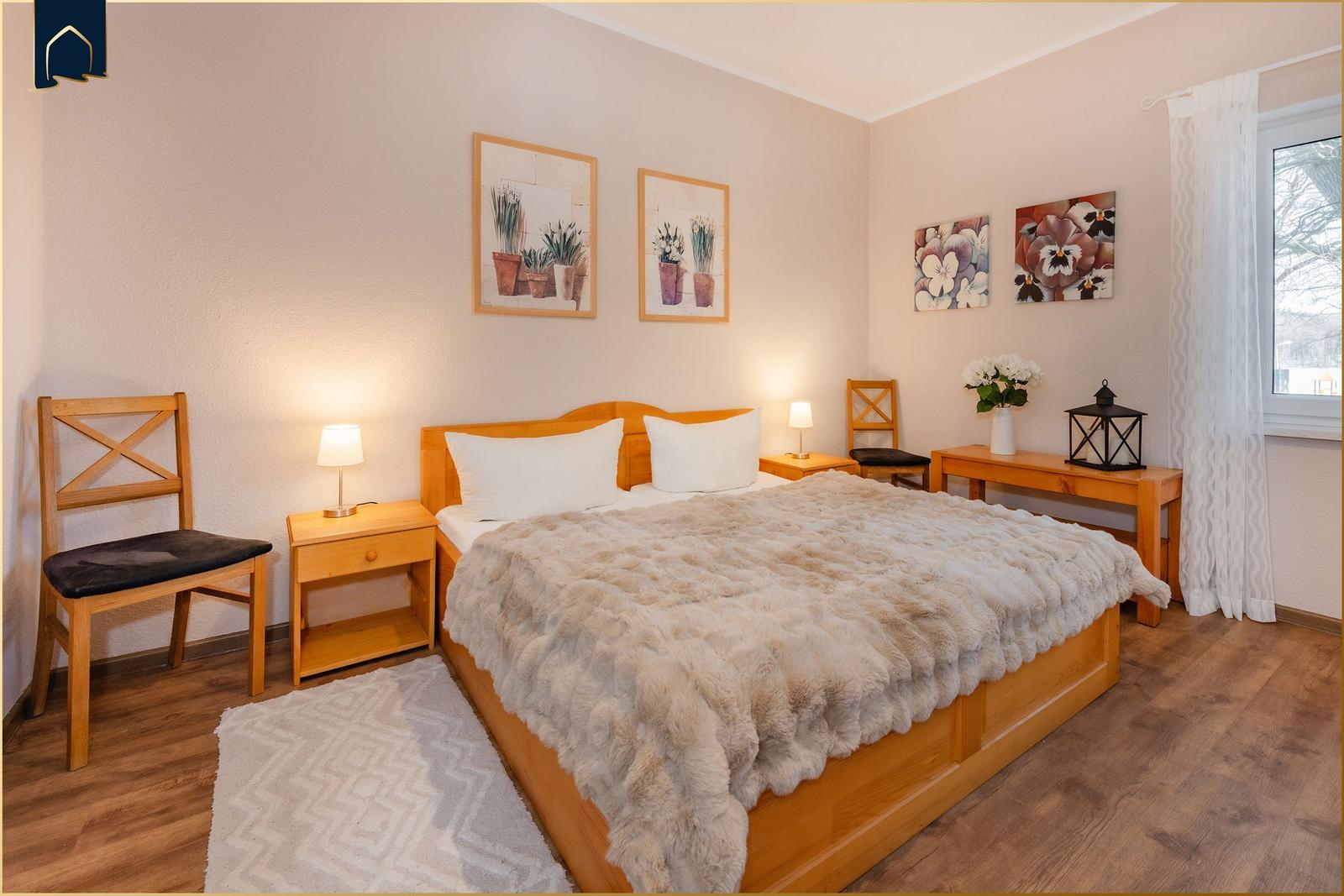 Schlafzimmer mit Holzbett, Nachttischen und Bildern an der Wand.