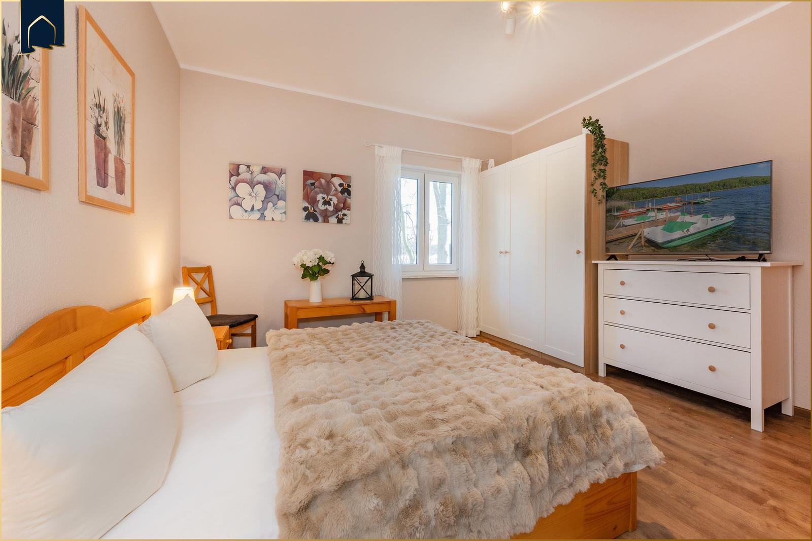 Schlafzimmer mit Bett, Kleiderschrank und Fernseher