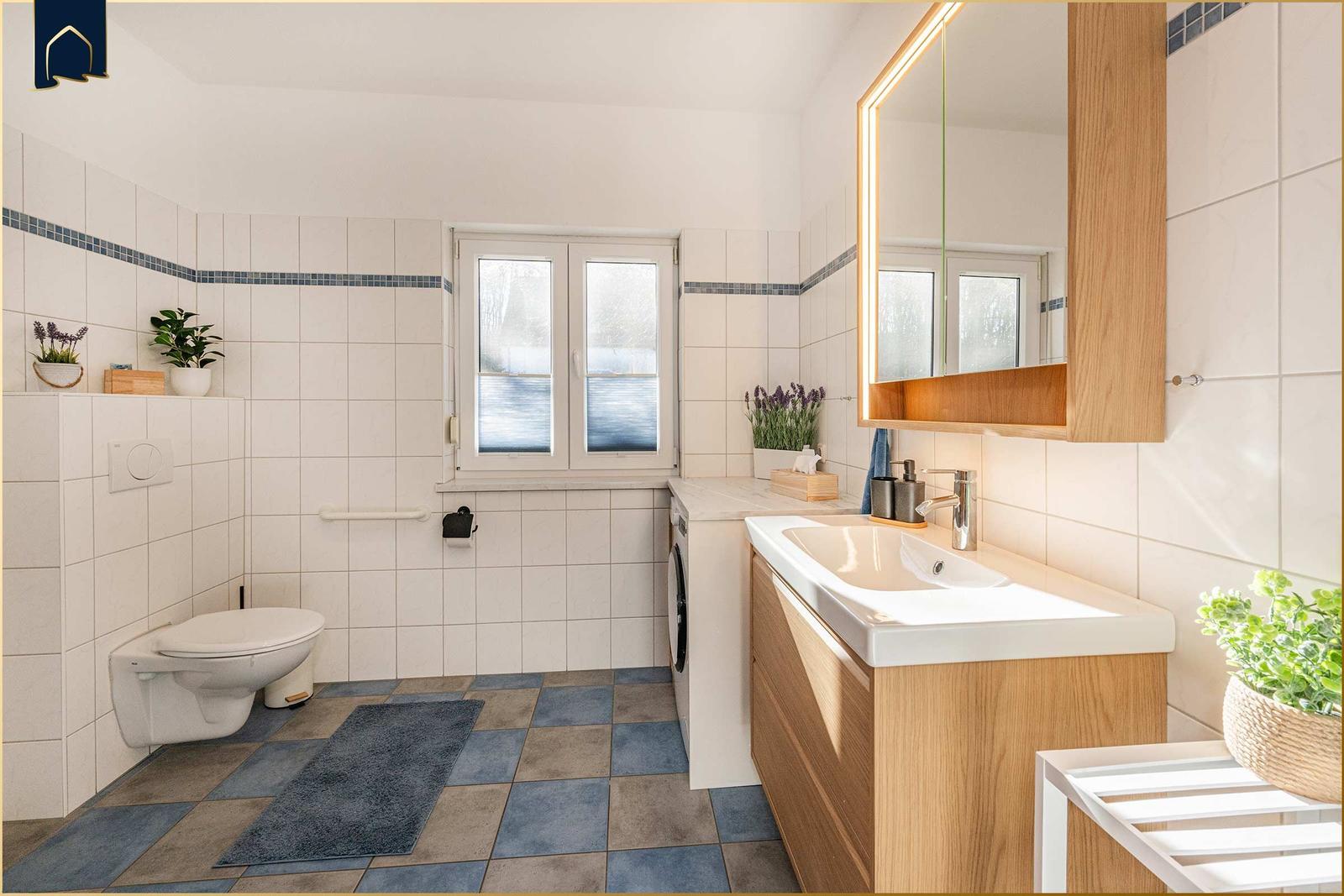Badezimmer mit Waschmaschine, Spiegel und Toilette