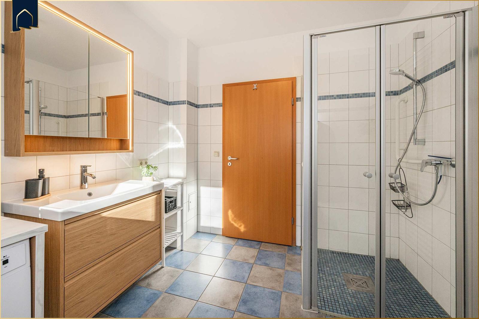 Bad mit Dusche, Waschbecken und Spiegel