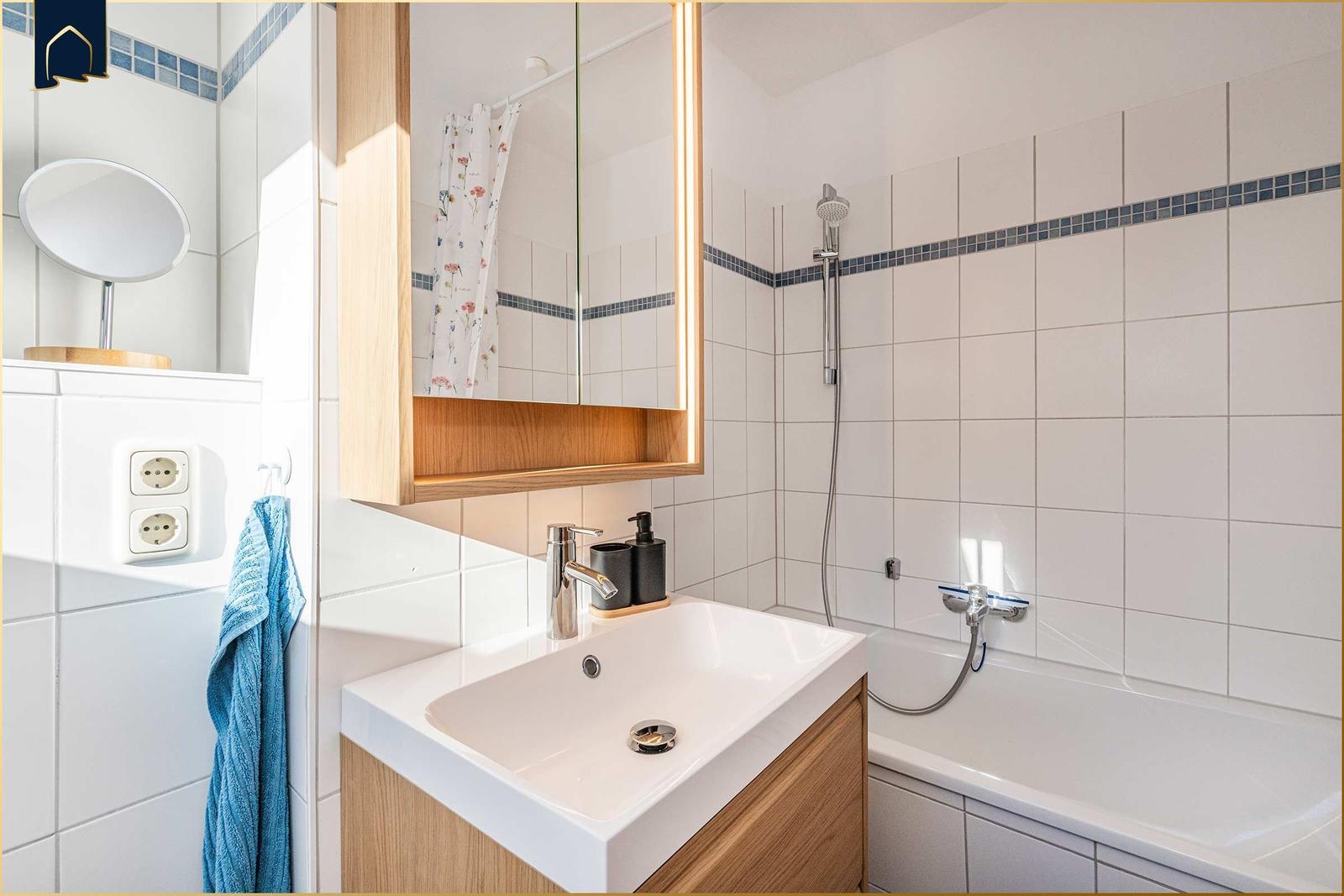 Badezimmer mit Badewanne, Dusche, Waschbecken und Spiegelschrank.