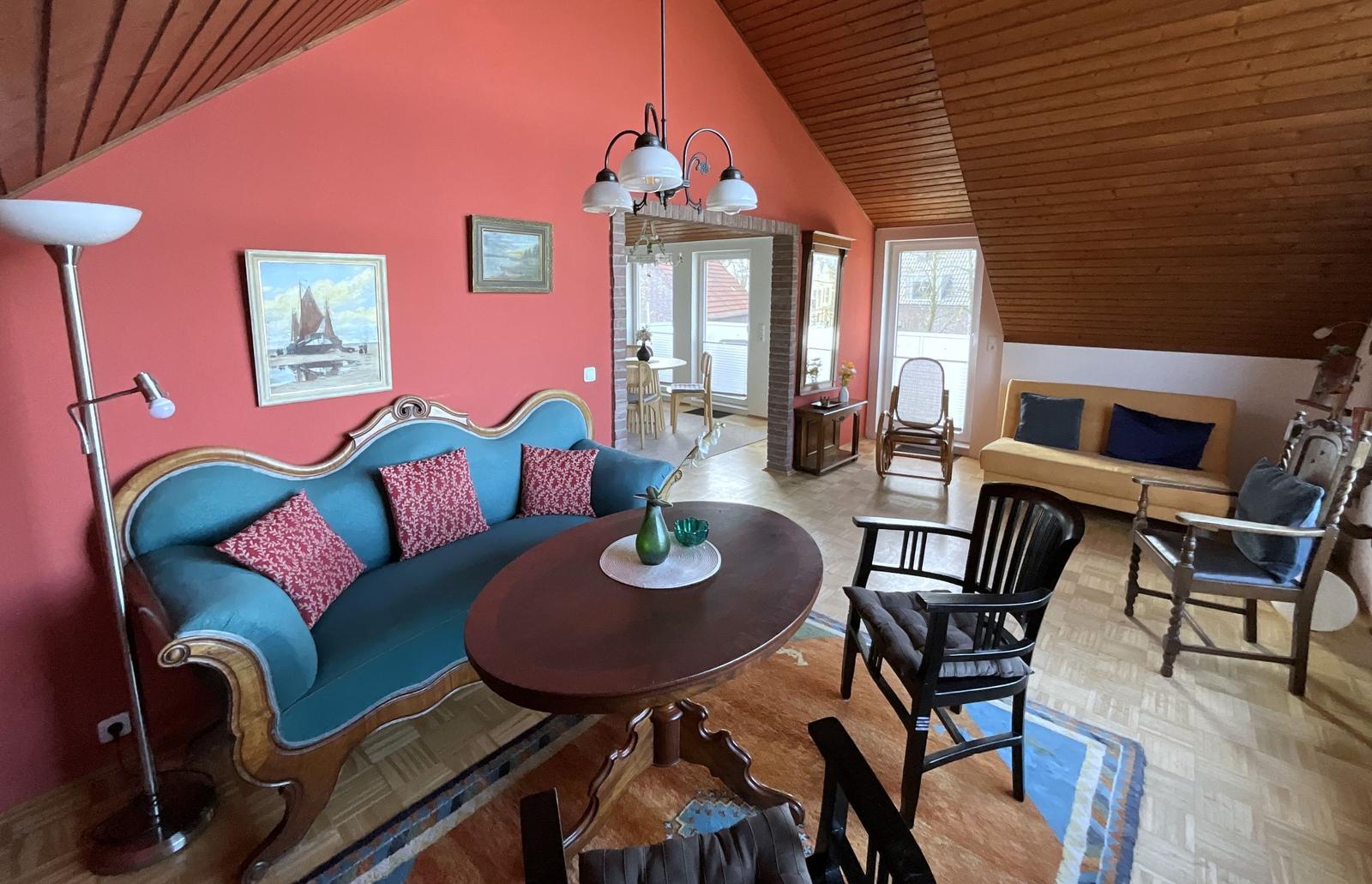 Wohnzimmer mit blauem Sofa, Holztisch und Sessel unter Holzdecke.