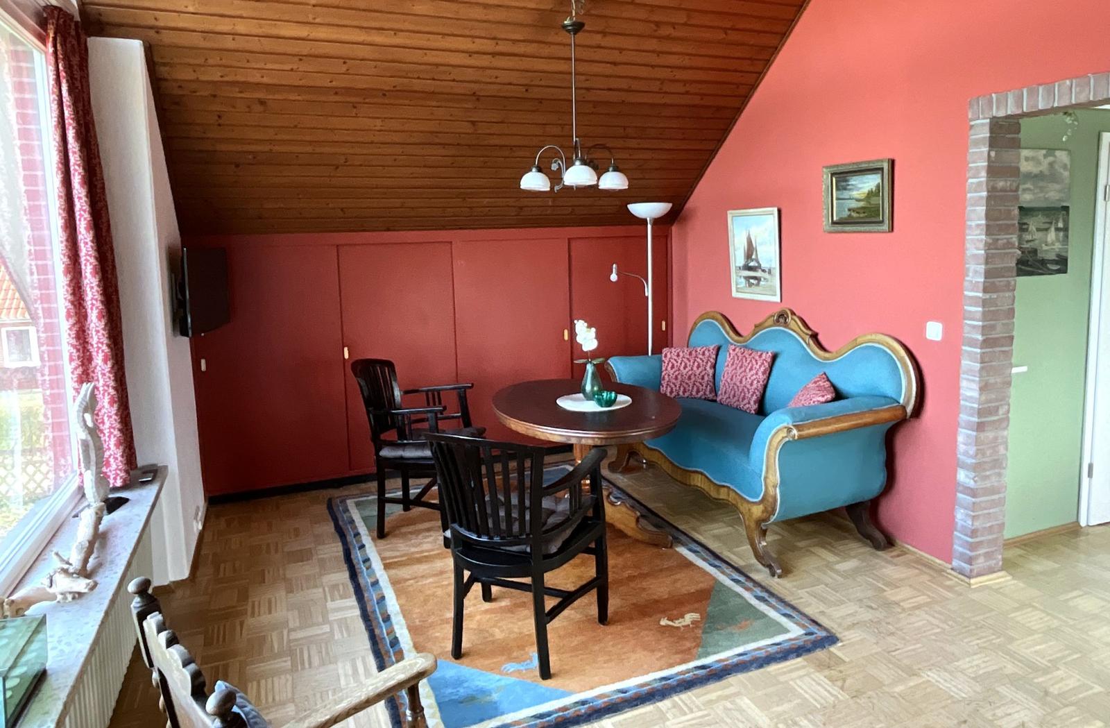 Wohnzimmer mit blauem Sofa, runden Tisch und Holzdecke.