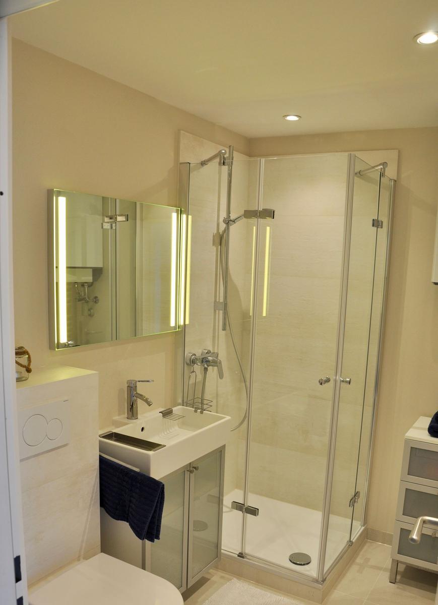 Badezimmer mit Dusche, Waschbecken und Spiegel