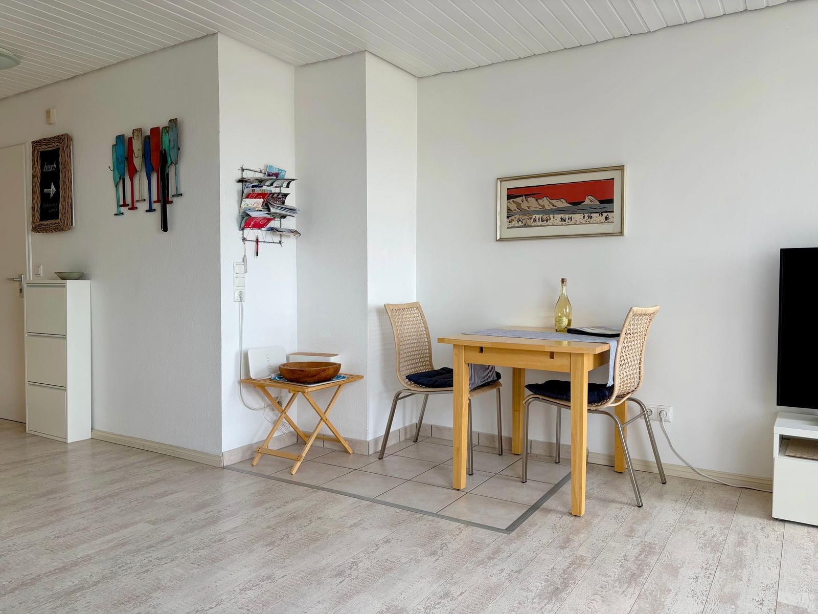 Essbereich mit Tisch, zwei Stühlen und Wanddekoration.