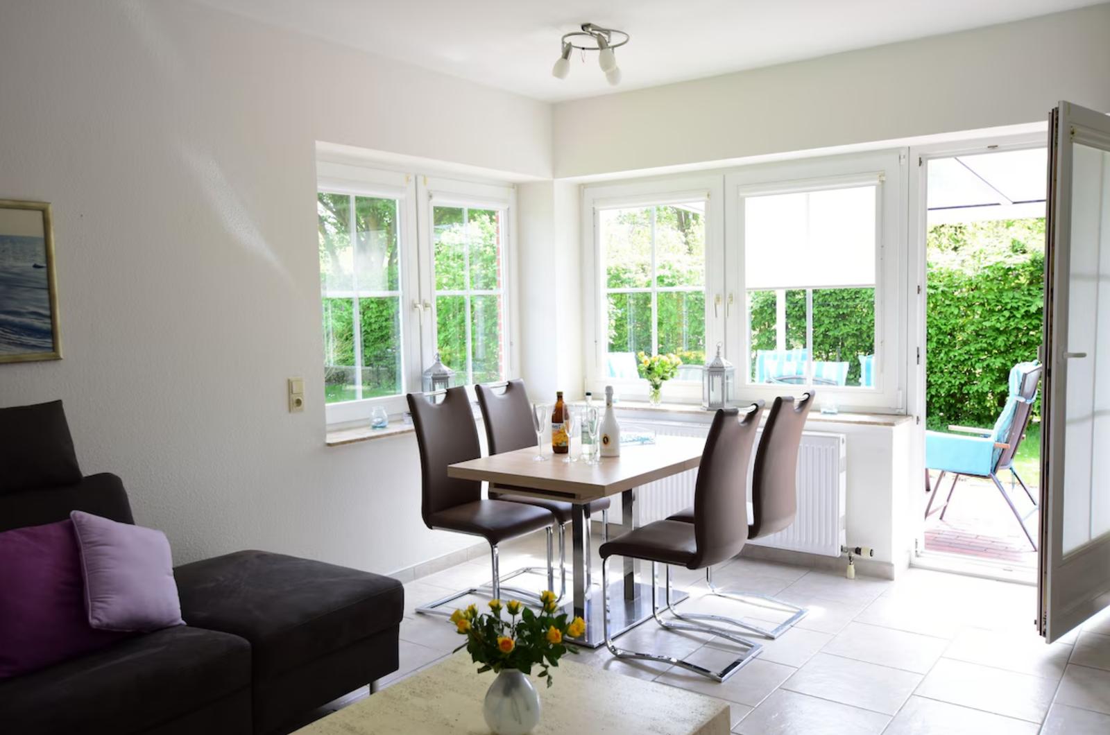 Wohn- und Essbereich mit Tisch, Stühlen und Blick auf Garten.