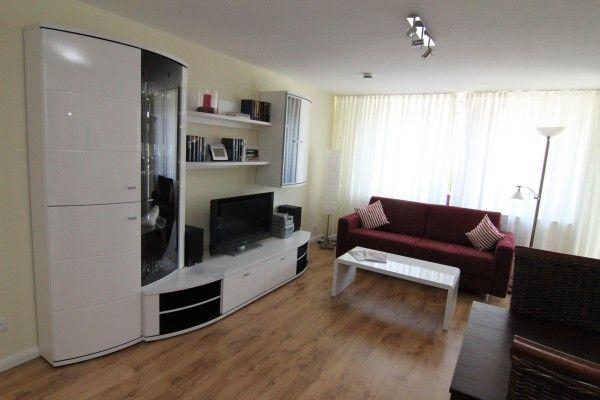 Wohnzimmer mit rotem Sofa, weißem Couchtisch und weißen Schränken.