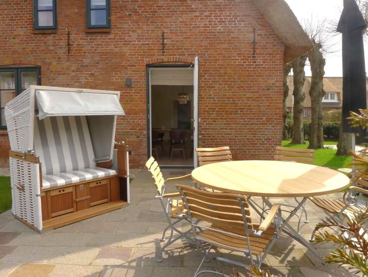 Terrasse mit Strandkorb und runden Tisch mit Stühlen vor Backsteinhaus