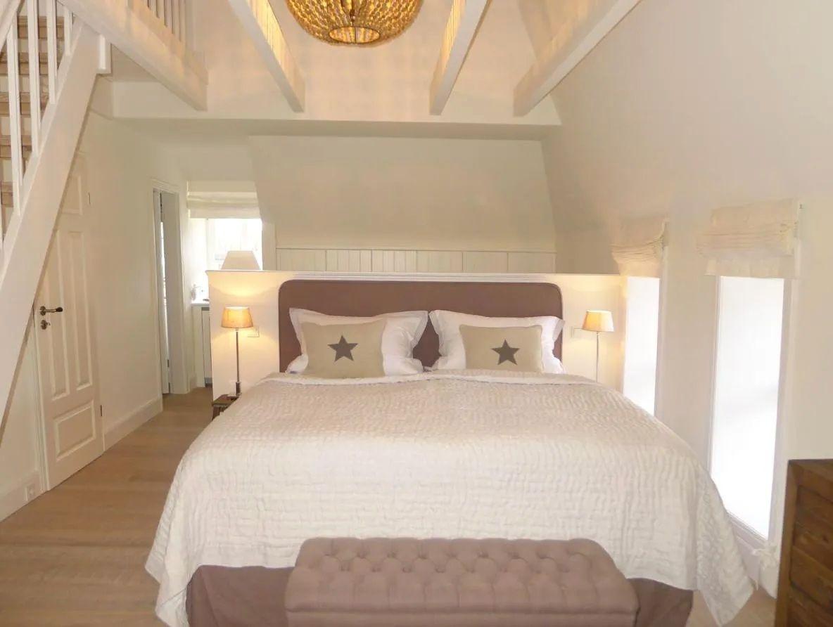 Schlafzimmer mit Bett, Nachttischlampen und Treppenhaus