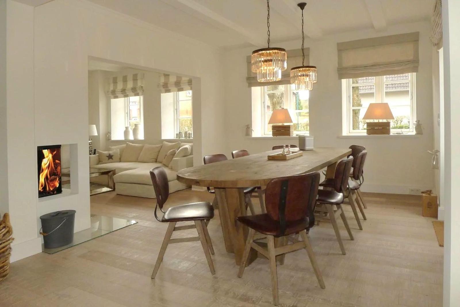 Esszimmer mit Holztisch und Stühlen, Sicht auf Wohnzimmer mit Sofa und Kamin.