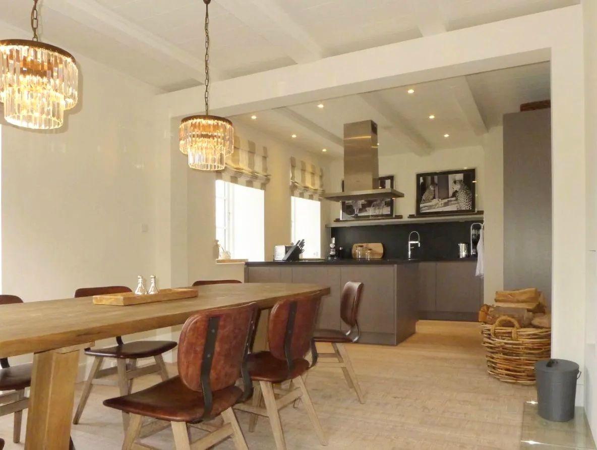 Essbereich mit Holztisch und Stühlen. Küche mit dunklen Schränken und Spüle.